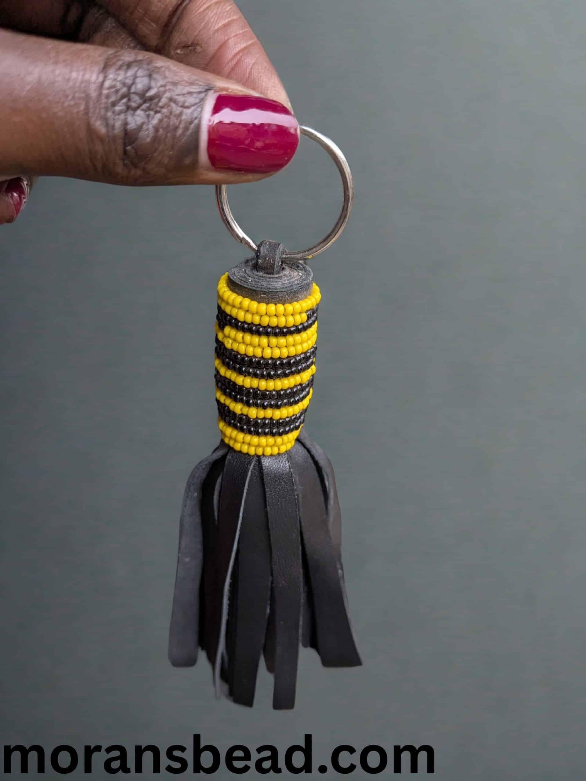 Beaded Maasai leather keychain with vibrant yellow and black beads, crafted ethically in Africa.